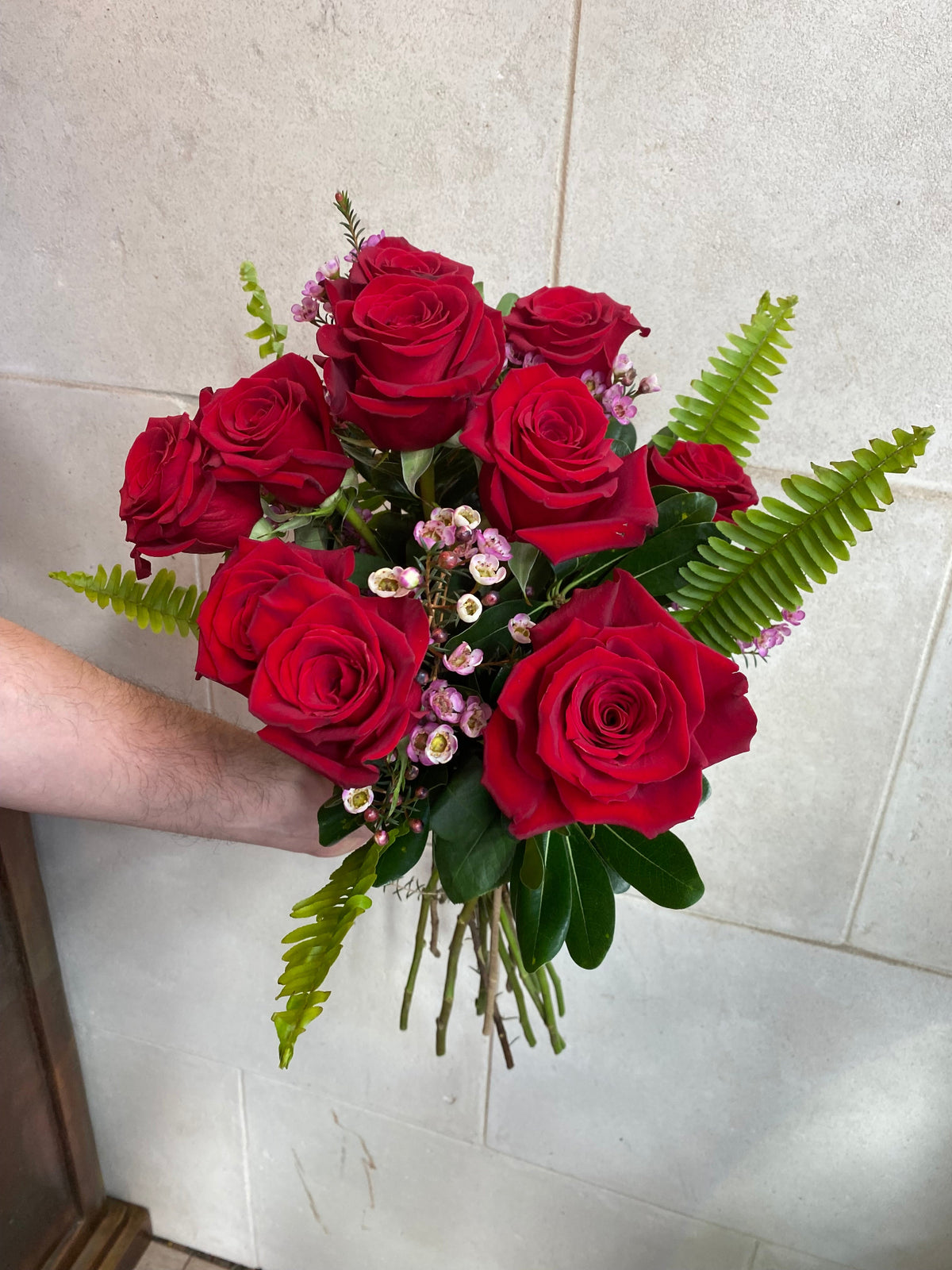 Dozen red roses with seasonal accent flowers and fresh greenery, available as a bouquet or vase arrangement.