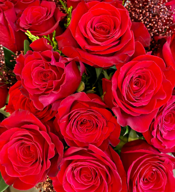 Dozen red roses with seasonal accent flowers and fresh greenery, available as a bouquet or vase arrangement.
