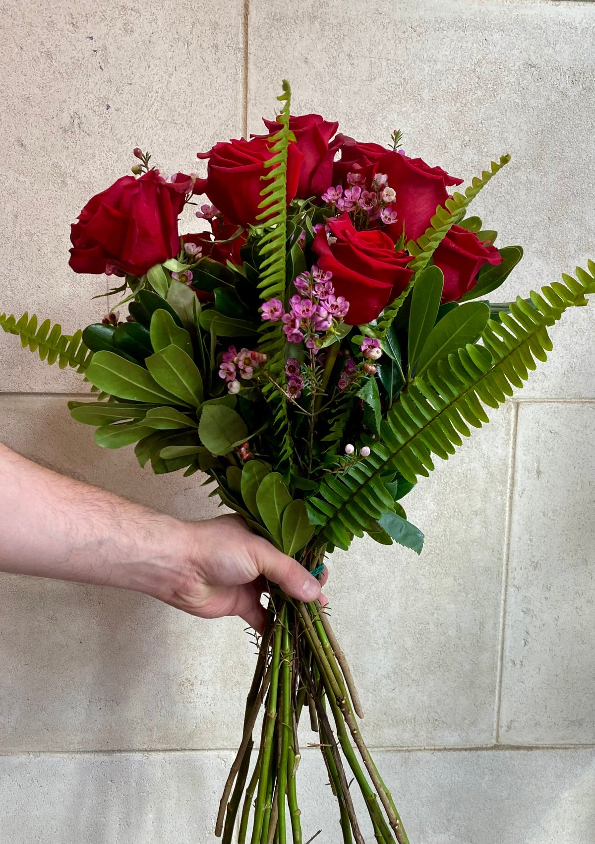 Dozen red roses with seasonal accent flowers and fresh greenery, available as a bouquet or vase arrangement.