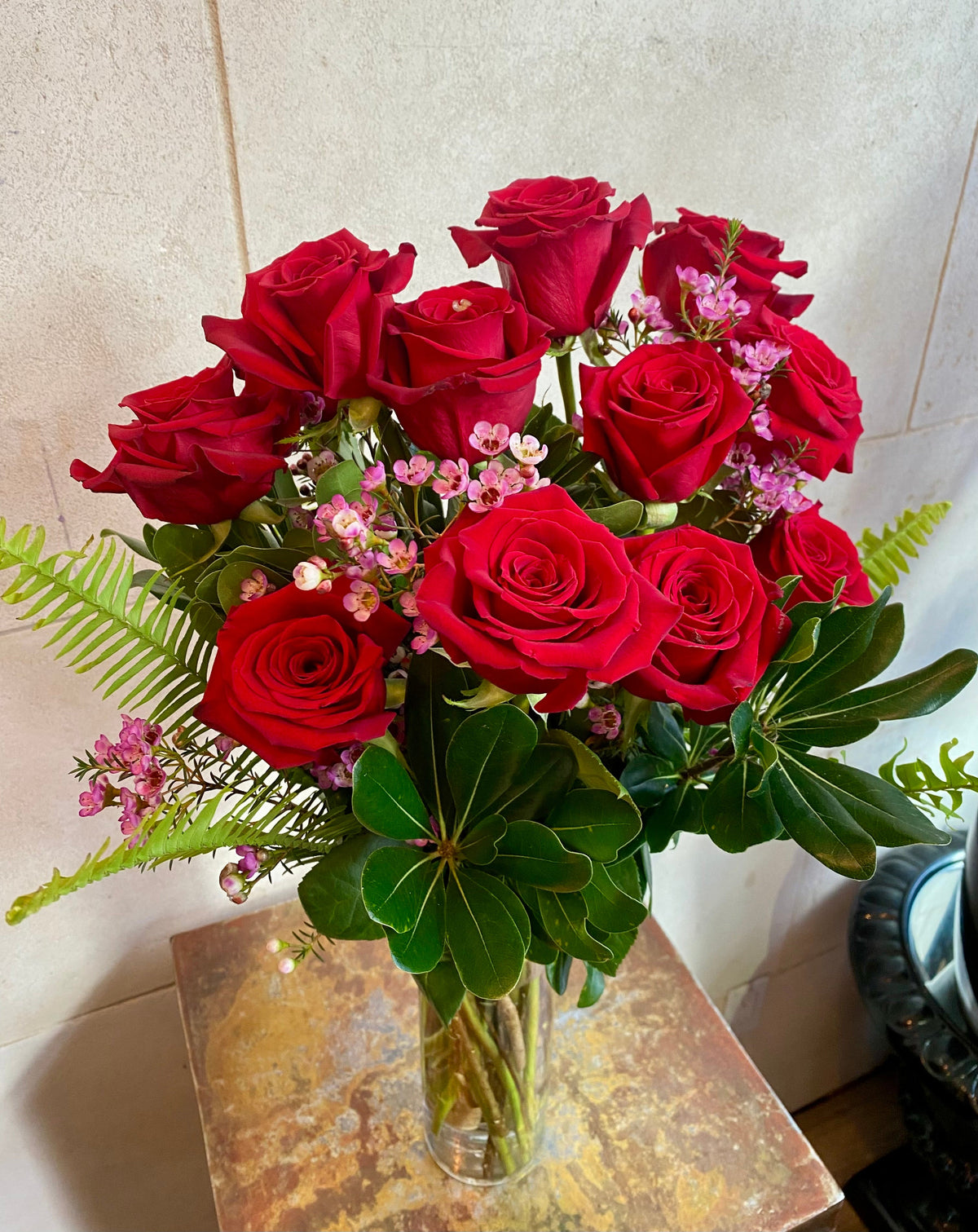 Dozen red roses with seasonal accent flowers and fresh greenery, available as a bouquet or vase arrangement.