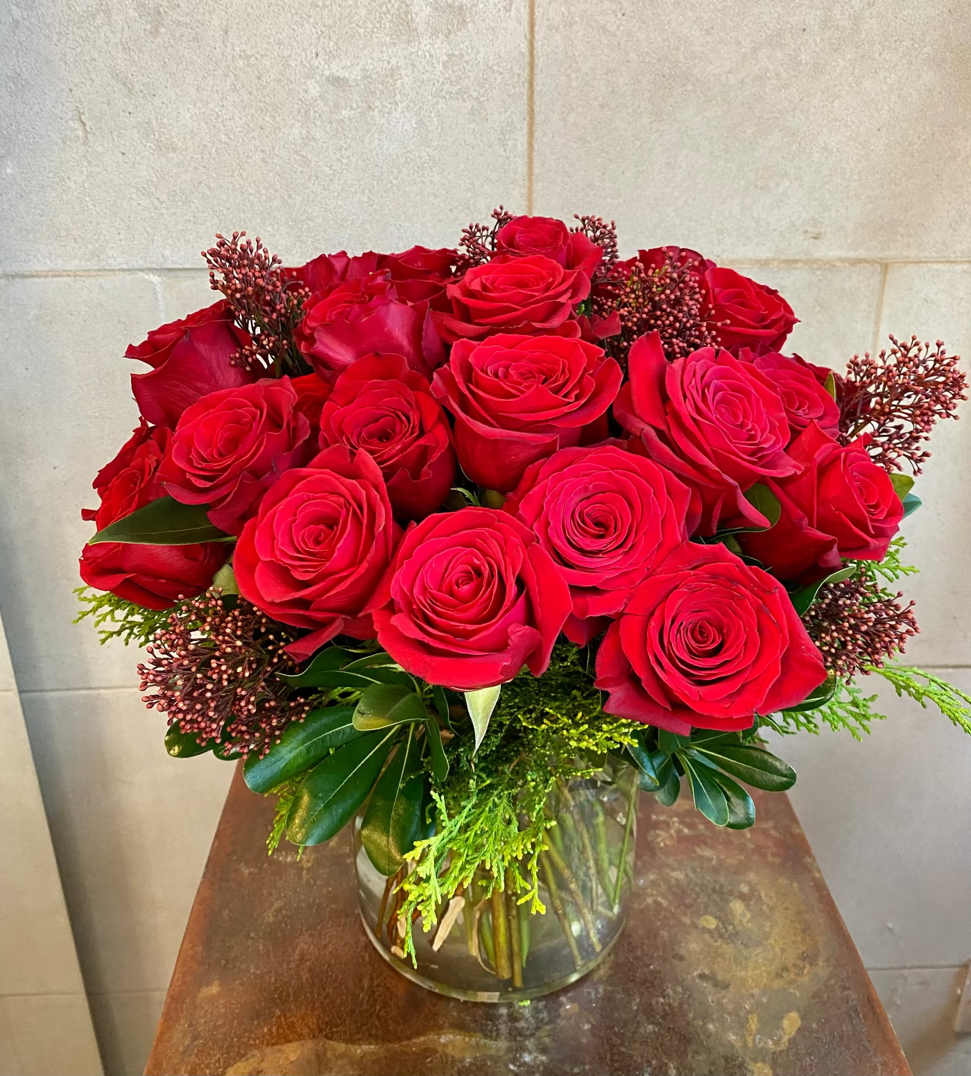 Red rose vase arrangement with premium greenery and seasonal accent flowers.