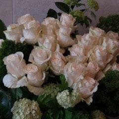 Dozen cream roses with premium greenery and seasonal accent flowers.