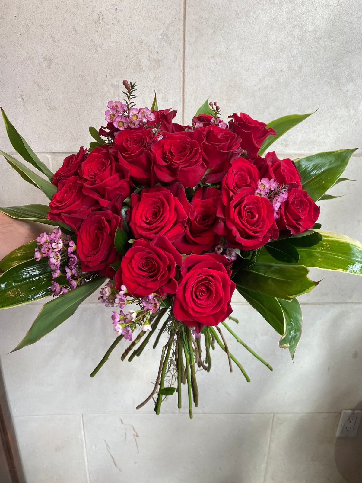 Dozen red roses with seasonal accent flowers and fresh greenery, available as a bouquet or vase arrangement.