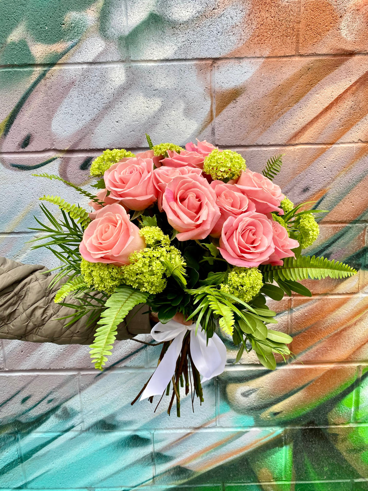 Dozen roses with seasonal accent flowers and fresh greenery, available as a hand-tied bouquet or vase arrangement.