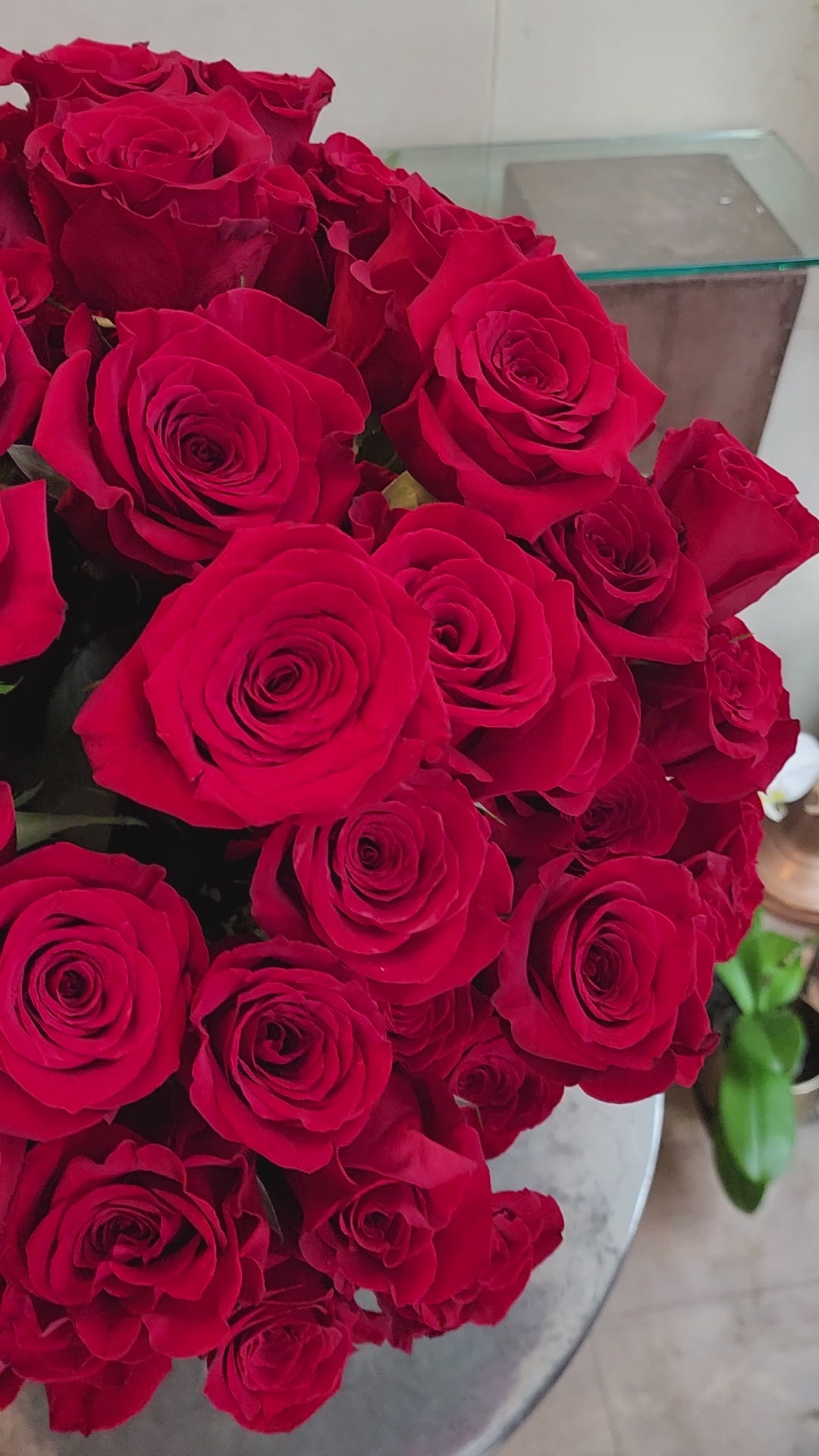 Large pavé arrangement of over 100 red roses with fresh greenery in a clear glass vase.