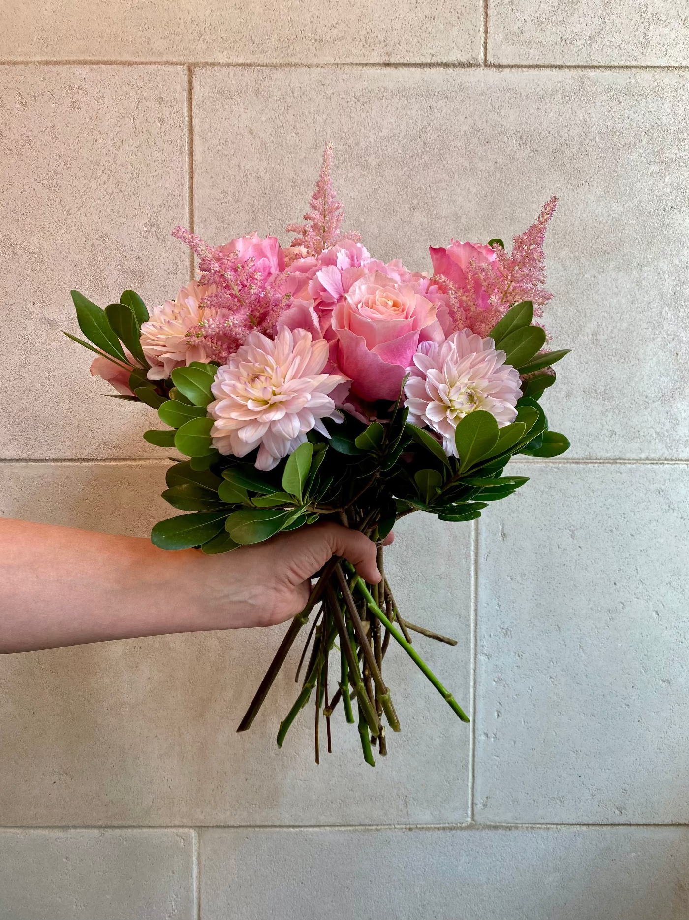 Hand-tied bouquet with pink hydrangeas, blush roses, dahlias, astilbe, and seasonal greenery.