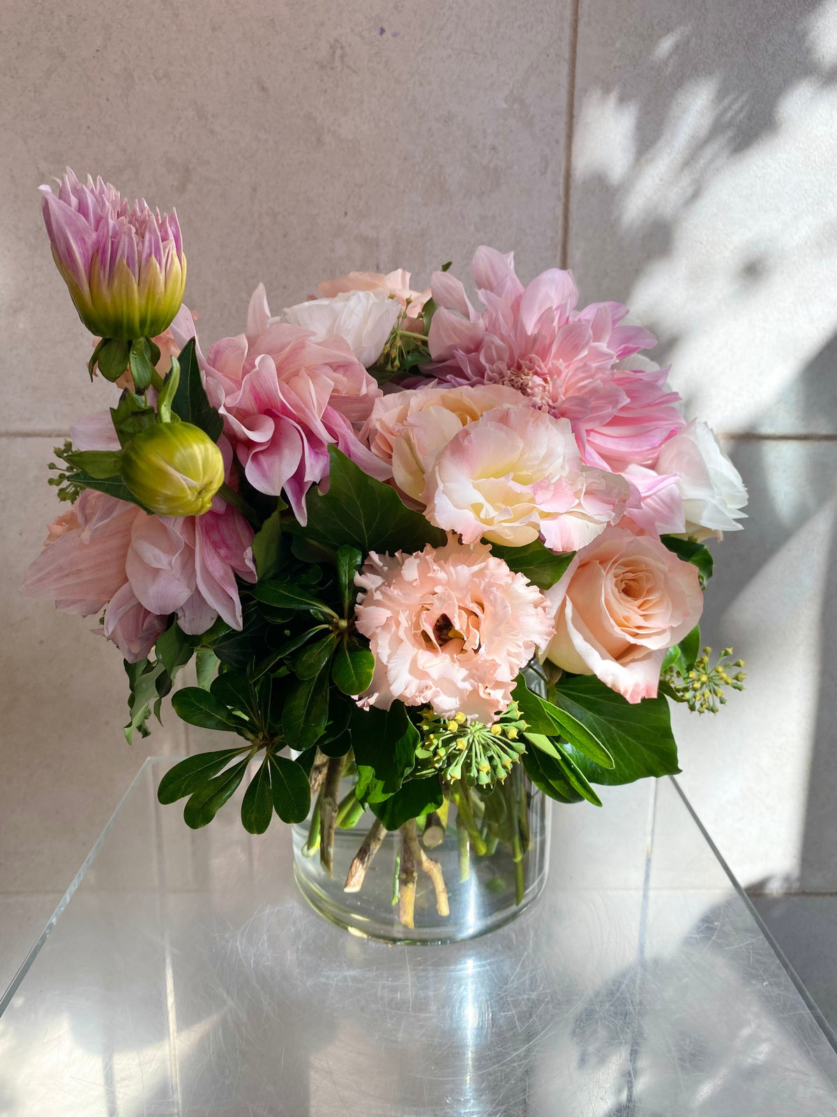 Soft pink floral arrangement with blush roses, pink dahlias, seasonal blooms, and fresh greenery.